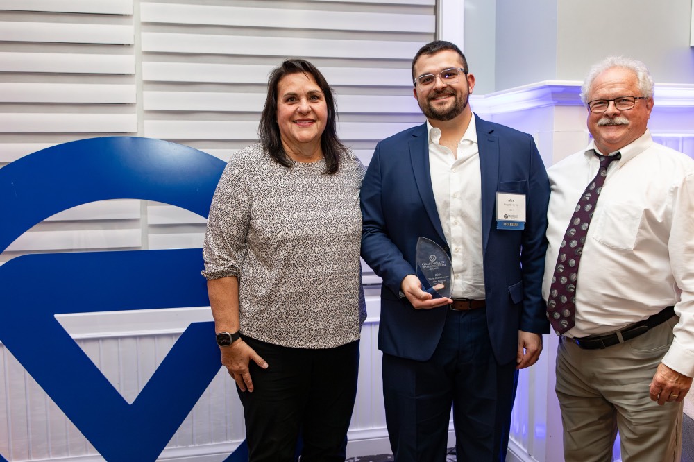 Alex Hogarth poses with family next to GVSU logo sign
